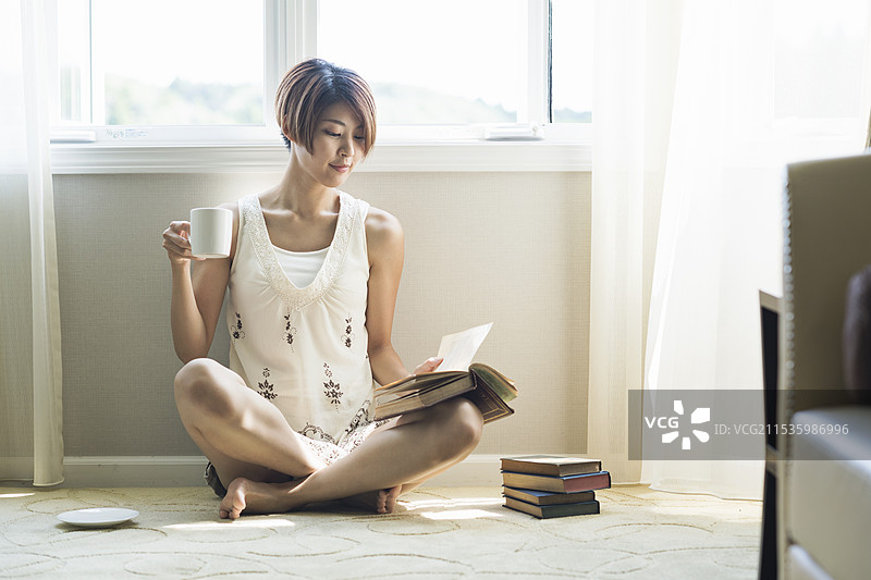 20多岁的女性在喝咖啡时阅读一本书图片素材