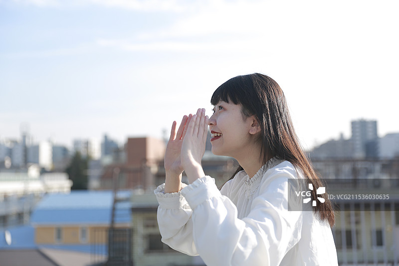 女人在屋顶上捂住嘴巴大喊图片素材