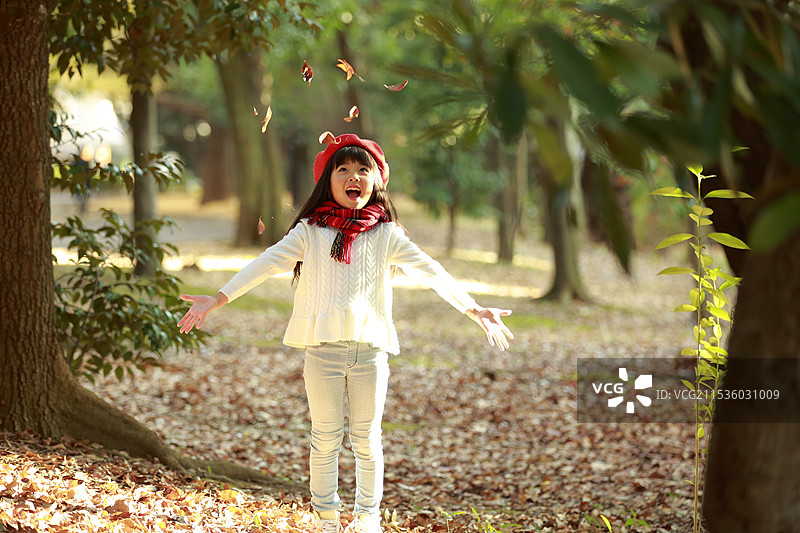 戴红贝雷帽的女孩在玩落叶图片素材
