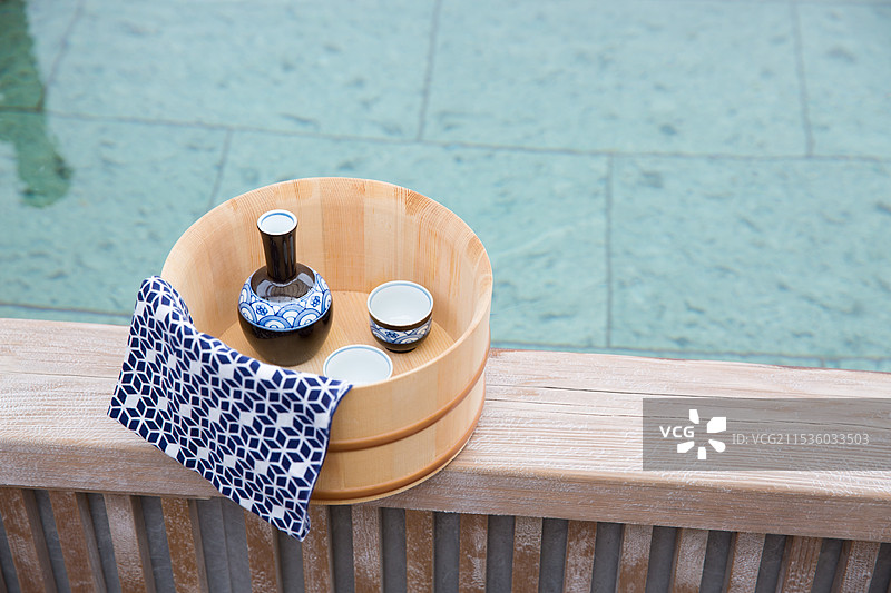 一个露天浴池，浴缸，浴缸里的清酒瓶和清酒杯图片素材