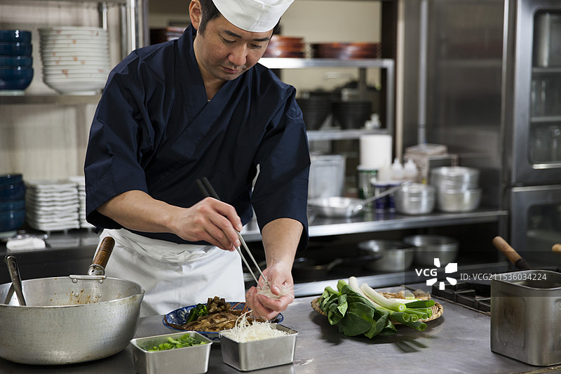 厨师将煮熟的鱼放在盘子上图片素材