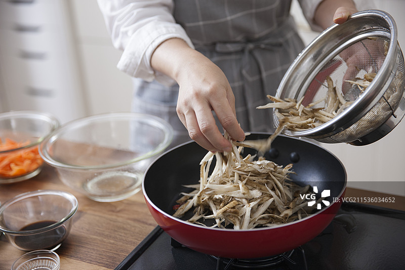 女人在平底锅中煎炒削好的牛蒡图片素材