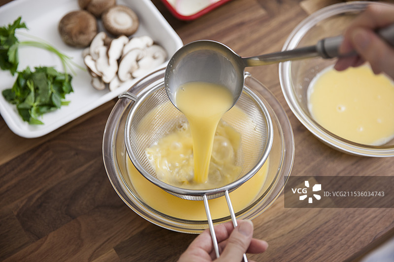 女人用高汤过滤蛋液。图片素材