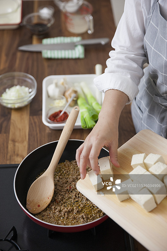 女人将豆腐放入炒碎肉中图片素材