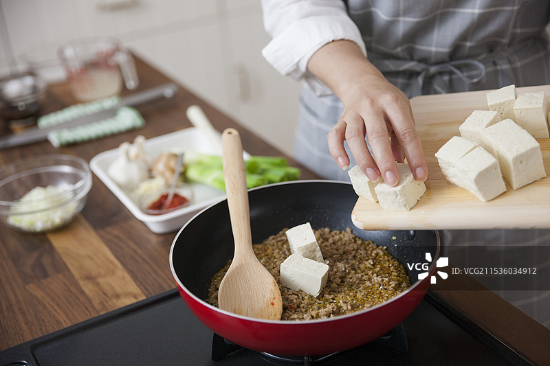 女人将豆腐放入炒碎肉中图片素材