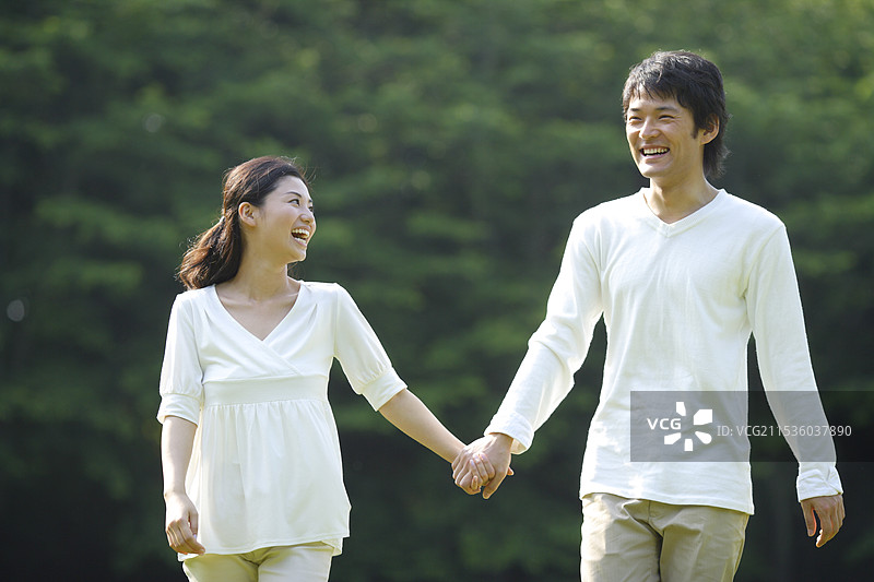 年轻男女在绿色环境中牵手图片素材