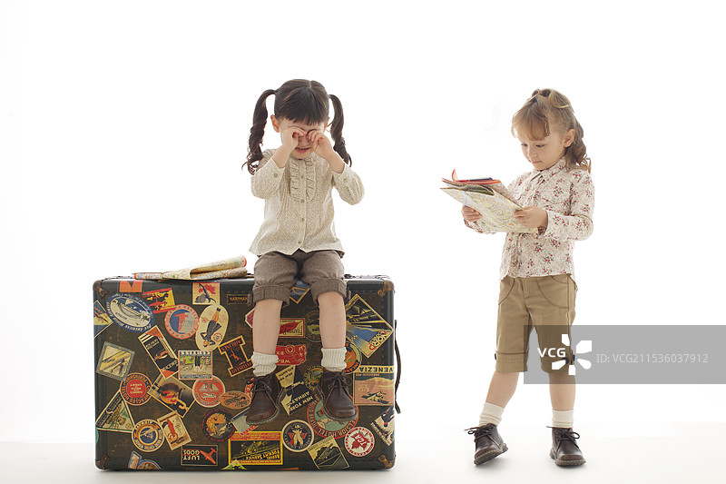 女孩坐在行李箱里哭泣，凝视着地图。图片素材