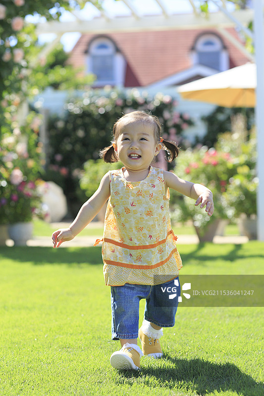女孩在大花园里奔跑，周围有草坪和玫瑰。图片素材