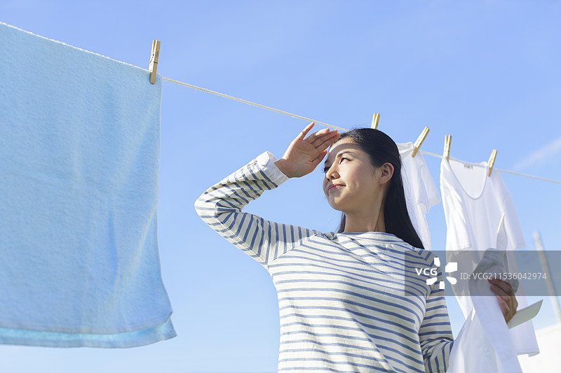家庭主妇在刺眼的阳光下晾衣服图片素材