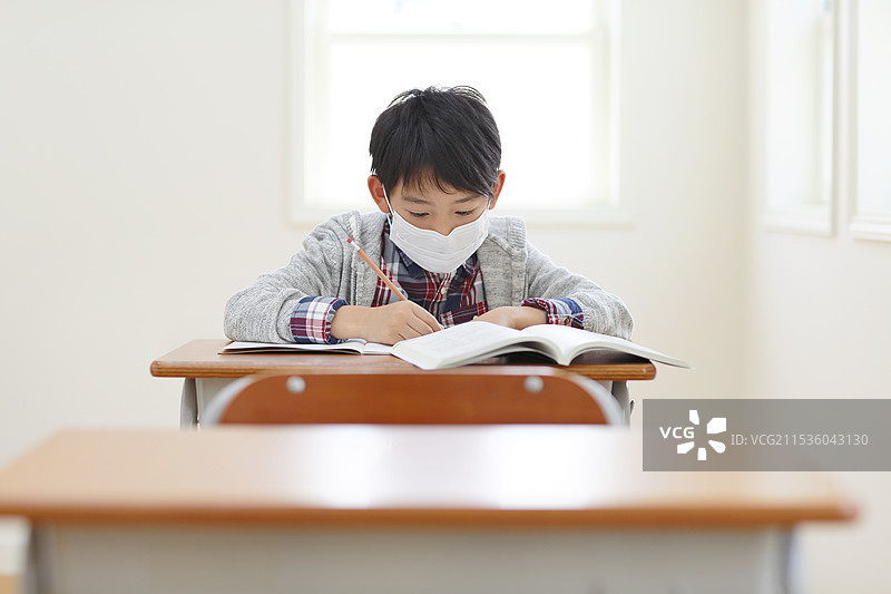 戴着口罩的生病学生和空着的课桌图片素材