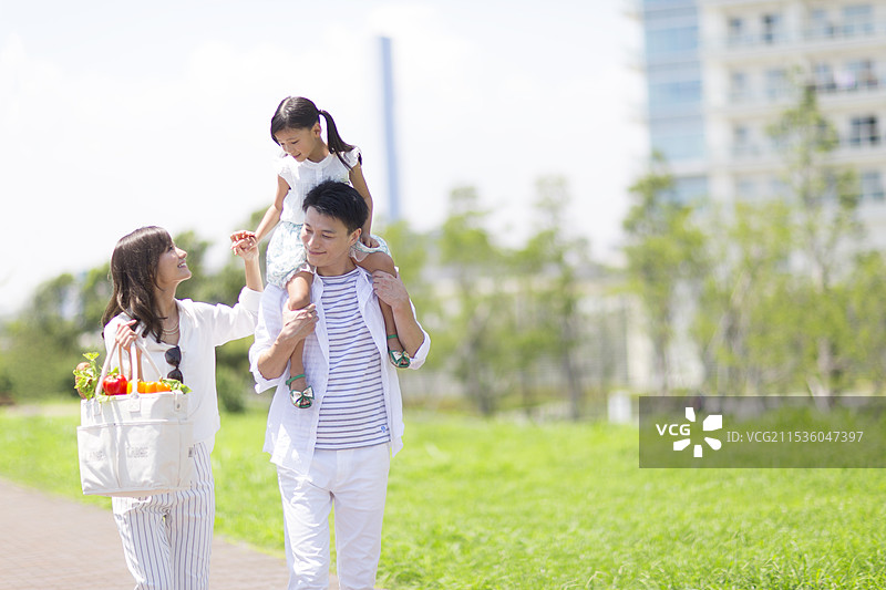 一家人在海滨长廊上肩扛着手推车散步图片素材