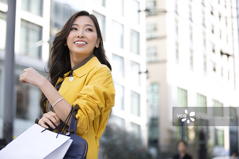 女人在街上回头看，手里提着购物袋图片素材