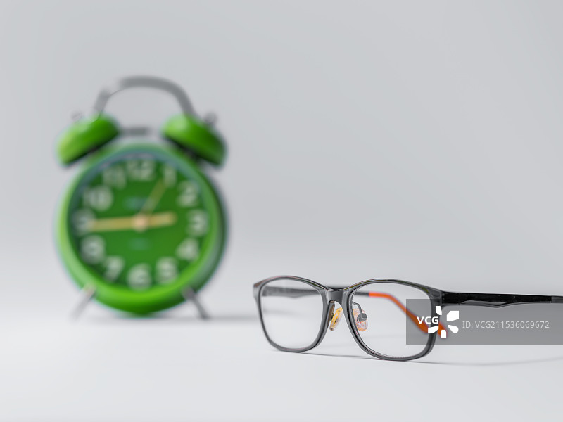 眼镜、绿色闹钟与白色背景留白图片素材