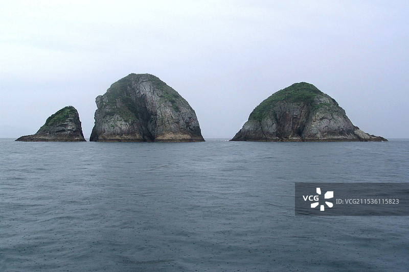 阴天平静海面上耸立的岛屿景象图片素材