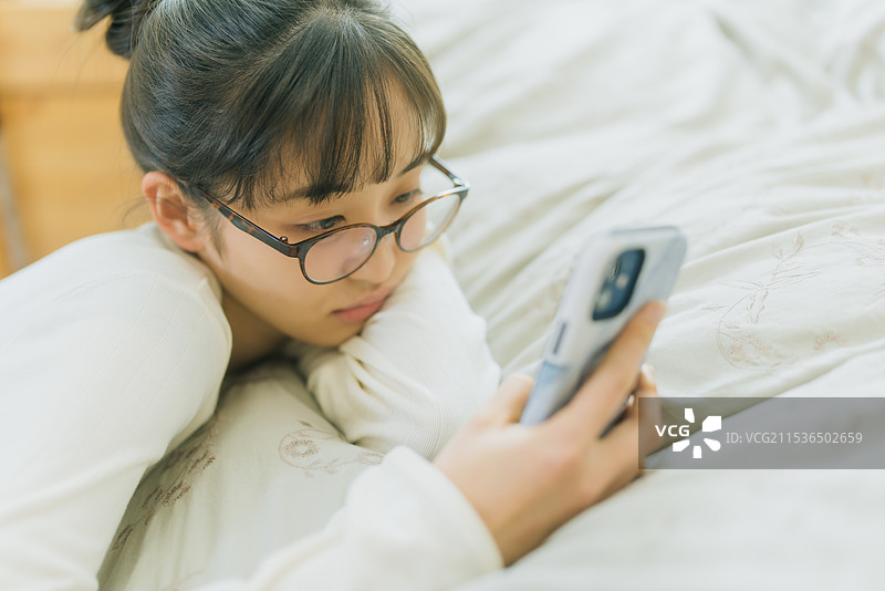 年轻女性在床上看智能手机图片素材
