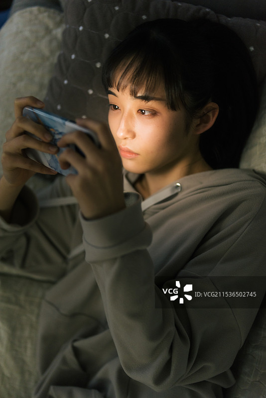年轻女性在夜晚关灯时看手机图片素材