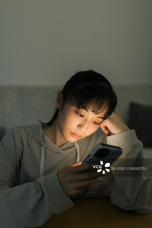 年轻女性在夜晚关灯时看手机图片素材