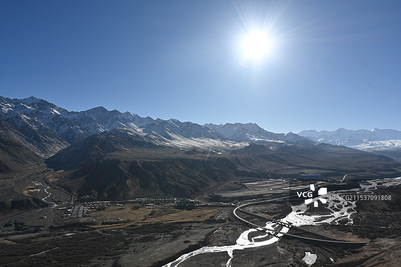 阳光照耀下的边境地区雪山及村落图片素材