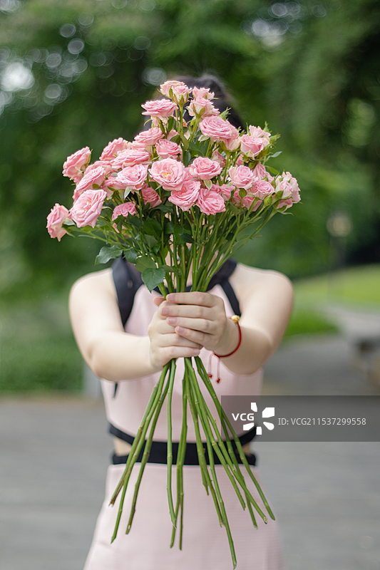 女人手举粉色玫瑰对着镜头图片素材