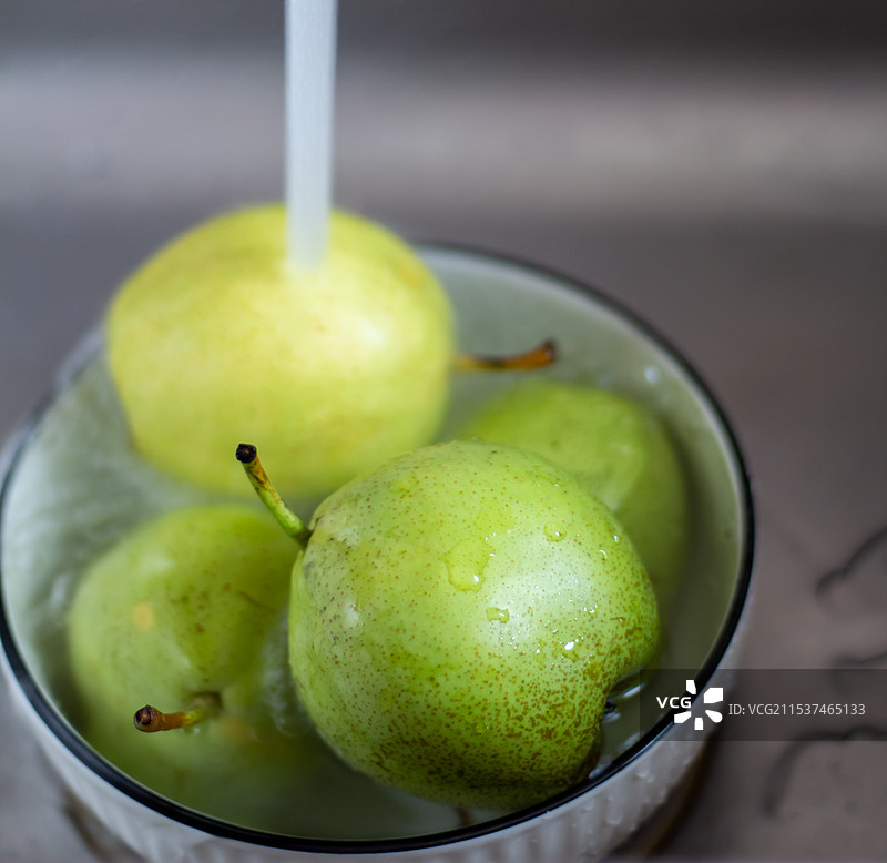 厨房水池中用碗清洗绿色水果梨图片素材