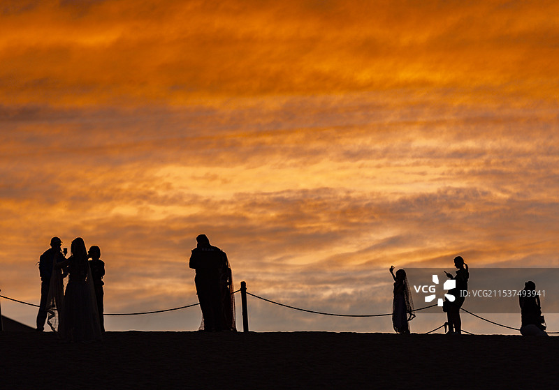 甘肃酒泉敦煌鸣沙山夕阳下的人群剪影图片素材