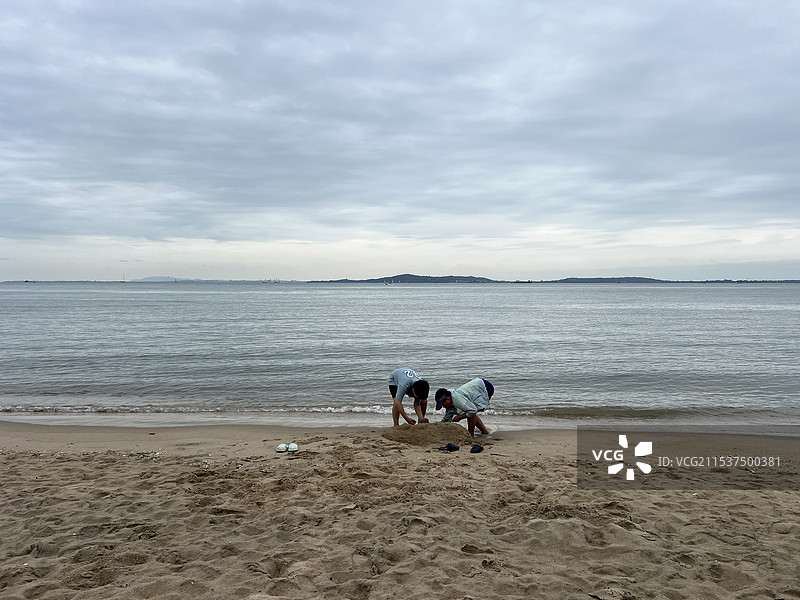 福建厦门海滩玩儿沙子的小孩子，对面是台湾图片素材