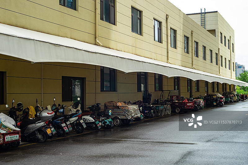 中国电动车拍摄主题，自行车停车场停车棚里，一排摩托车和自行车，户外白昼无人图像摄影图片素材
