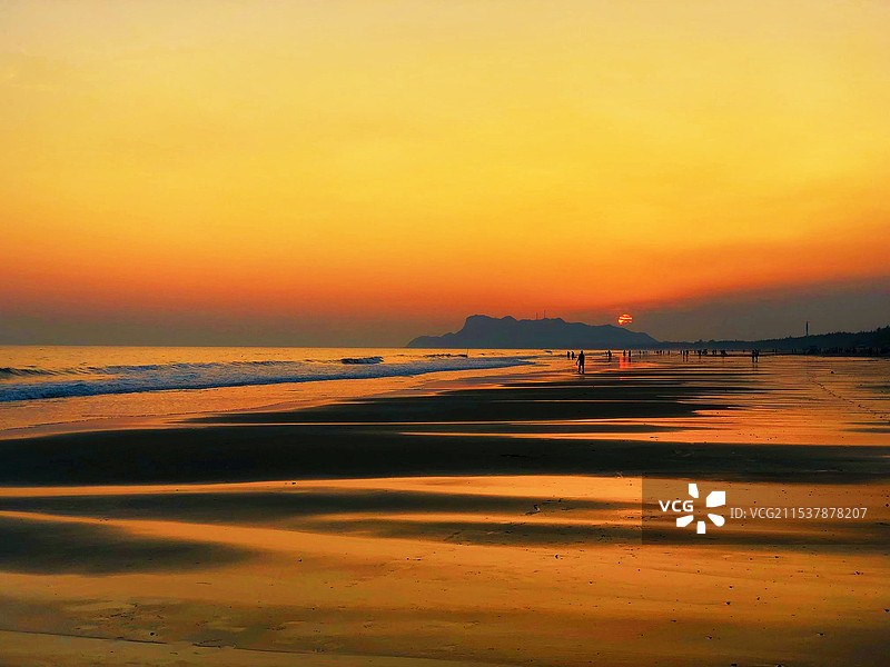 日落时海滩上的人们在天空的映衬下剪影图片素材