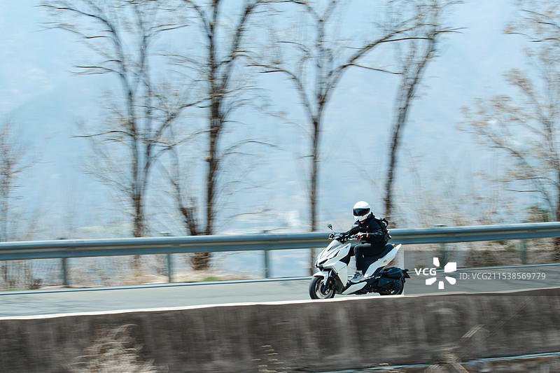 中国城市道路交通拍摄主题，正在骑摩托车的人迅速骑过拖影效果，户外白昼无人图像摄影图片素材