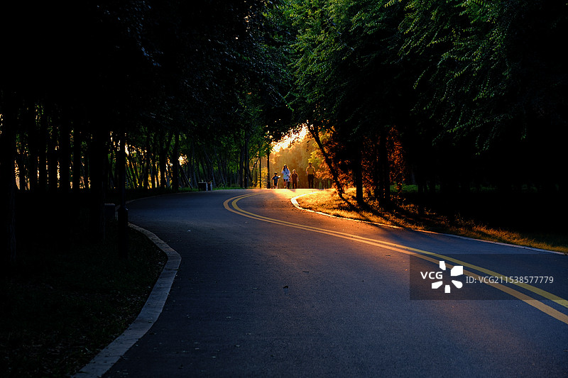 夕阳西下。漫步在城市绿道的人们图片素材