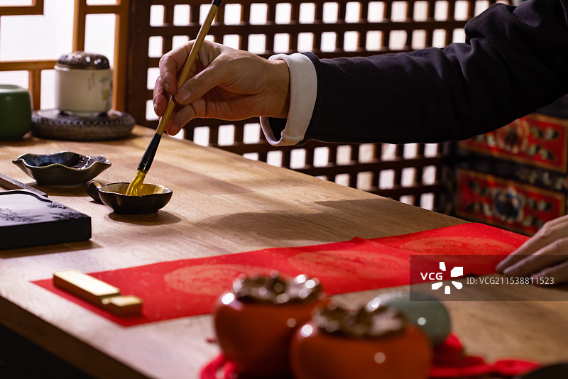 一个东方人在书房里蘸墨写春联图片素材
