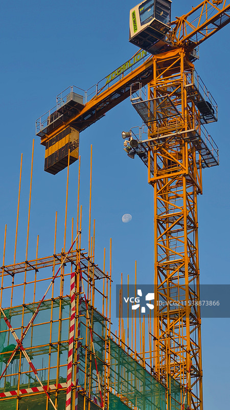 清晨建筑工地吊塔与蓝天中的月亮图片素材