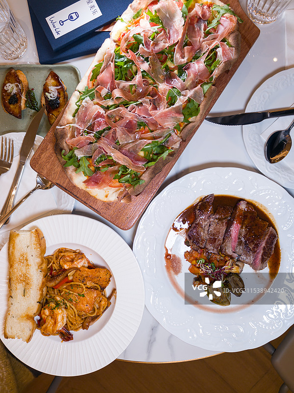 丰盛的西式餐桌包含披萨意面和牛排图片素材