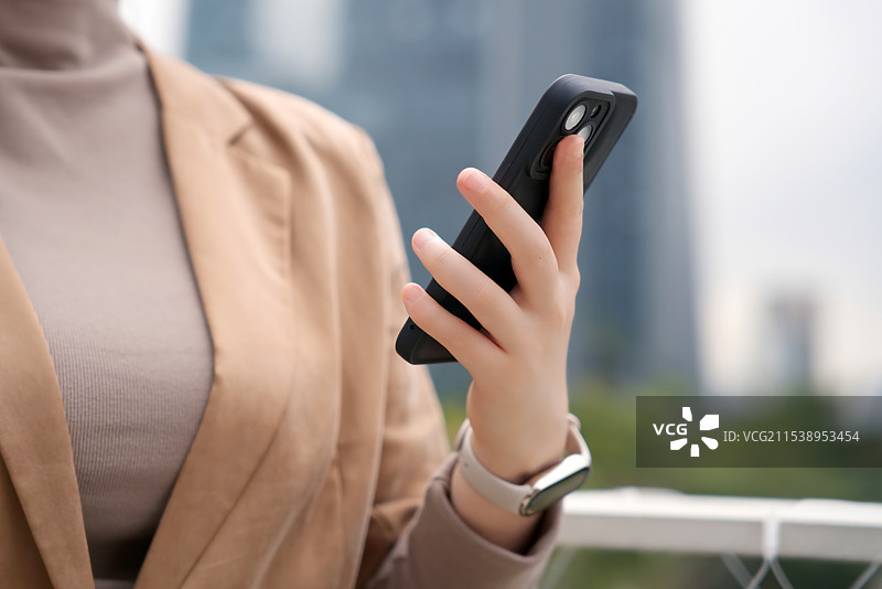 年轻女子在户外使用智能手机，时尚现代图片素材