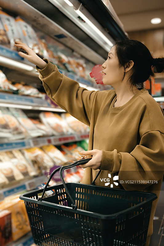 年轻女子在现代超市愉快地购物图片素材