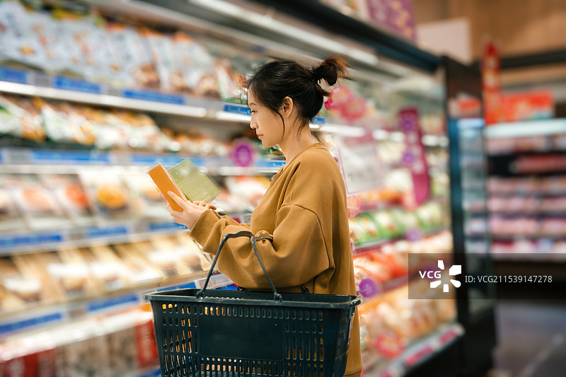 年轻女子在现代超市愉快地购物图片素材