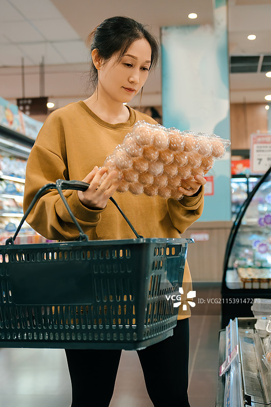 年轻女子在现代超市愉快地购物图片素材