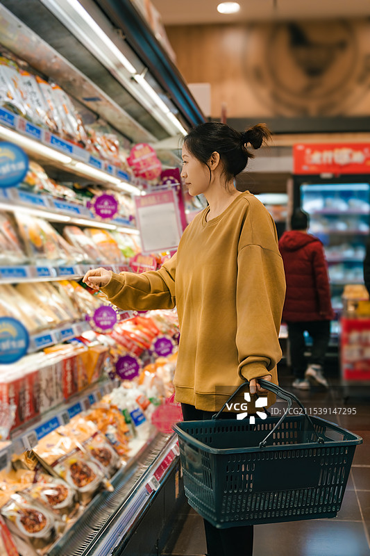 年轻女子在现代超市愉快地购物图片素材
