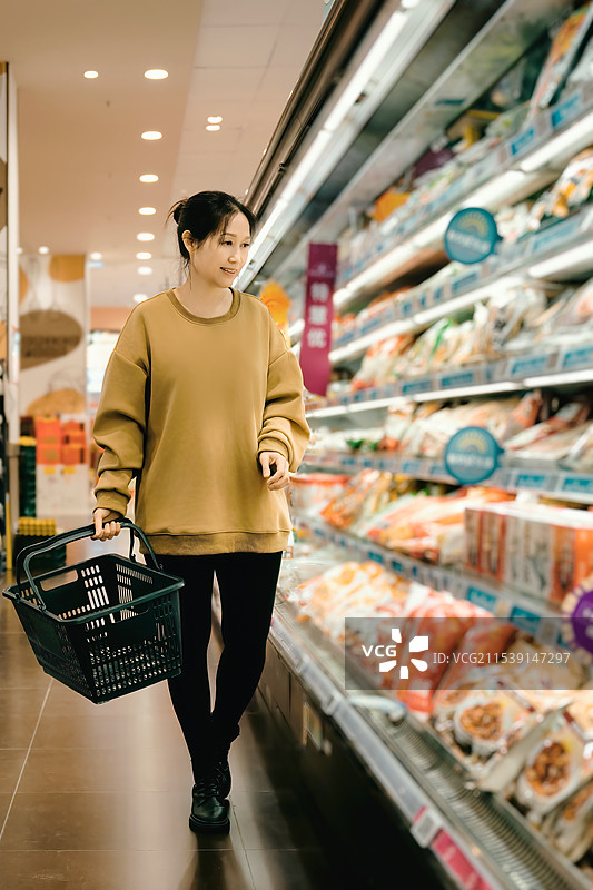年轻女子在现代超市愉快地购物图片素材