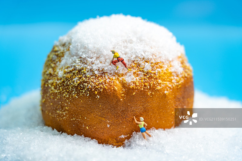 登山小人在勇敢攀登面包做的雪山微缩场景，奋勇拼搏勇攀高峰图片素材