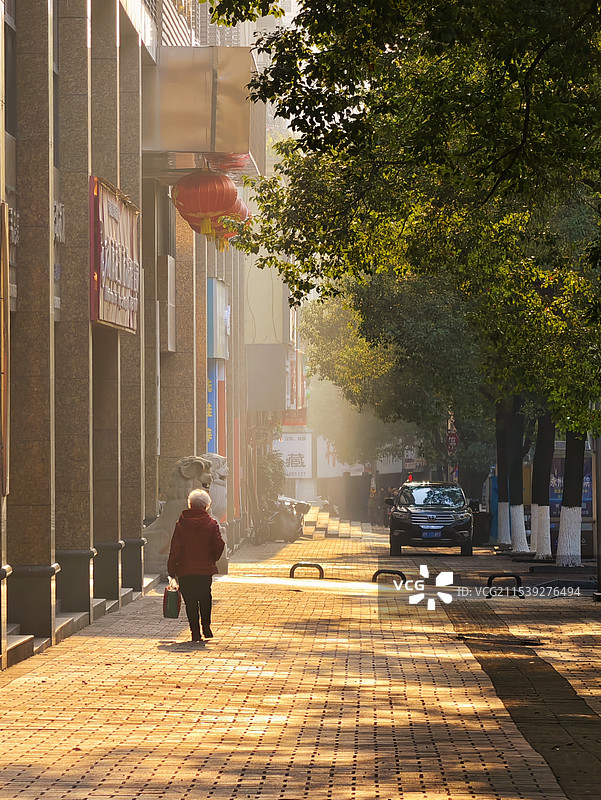 朝阳下的漫步在冬日朝阳下，一位老人漫步在古老的街道上，享受着宁静与平和的时光。摄于冷水滩梅湾路！图片素材