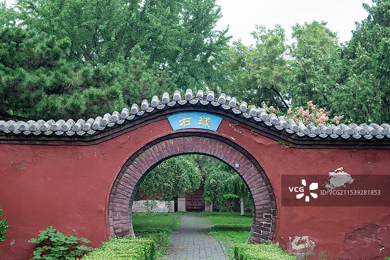 中国山东泰安著名景点泰山第一行宫岱庙，中式庭院里左缘和右缘月亮门和花坛，户外白昼无图片素材