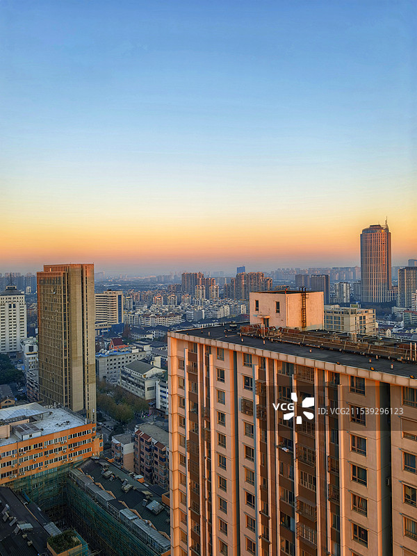 利用窗户的角度，拍摄日出时，城市建筑物在晨光下的景色图片素材