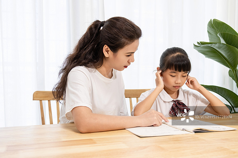 一名妈妈辅导孩子写作业时很苦恼图片素材