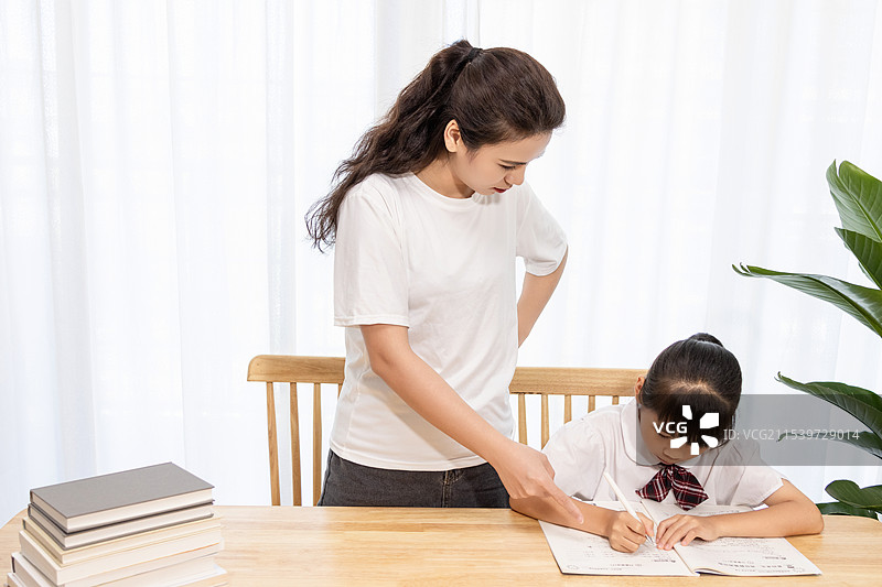 一名妈妈辅导孩子写作业时很苦恼图片素材