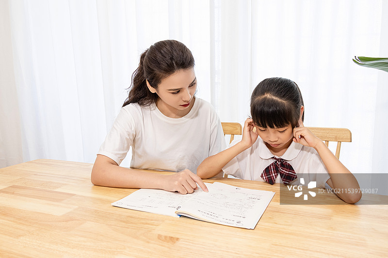 一名妈妈辅导孩子写作业时很苦恼图片素材