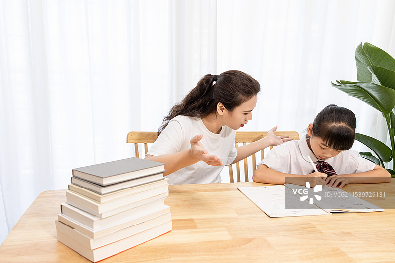 一名妈妈辅导孩子写作业时很苦恼图片素材