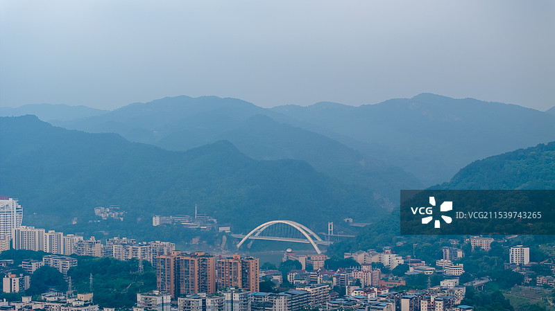 云雾中，航拍山地城市重庆北碚城区城市天际线、城市高楼大厦、车水马龙的交通、远处的高山图片素材