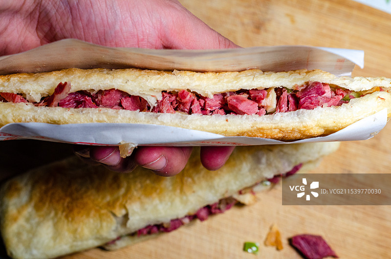 手里拿起一个河间驴肉火烧图片素材