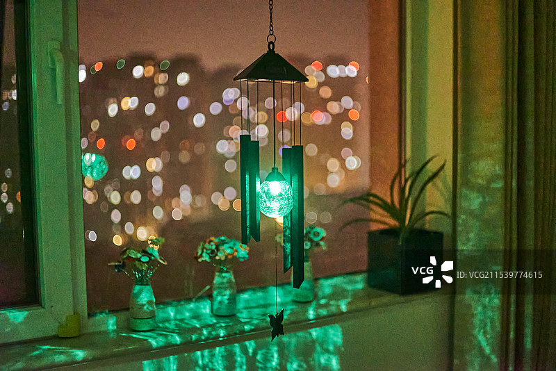 居家环境下一个风铃小夜灯和窗外宁静的城市夜晚图片素材